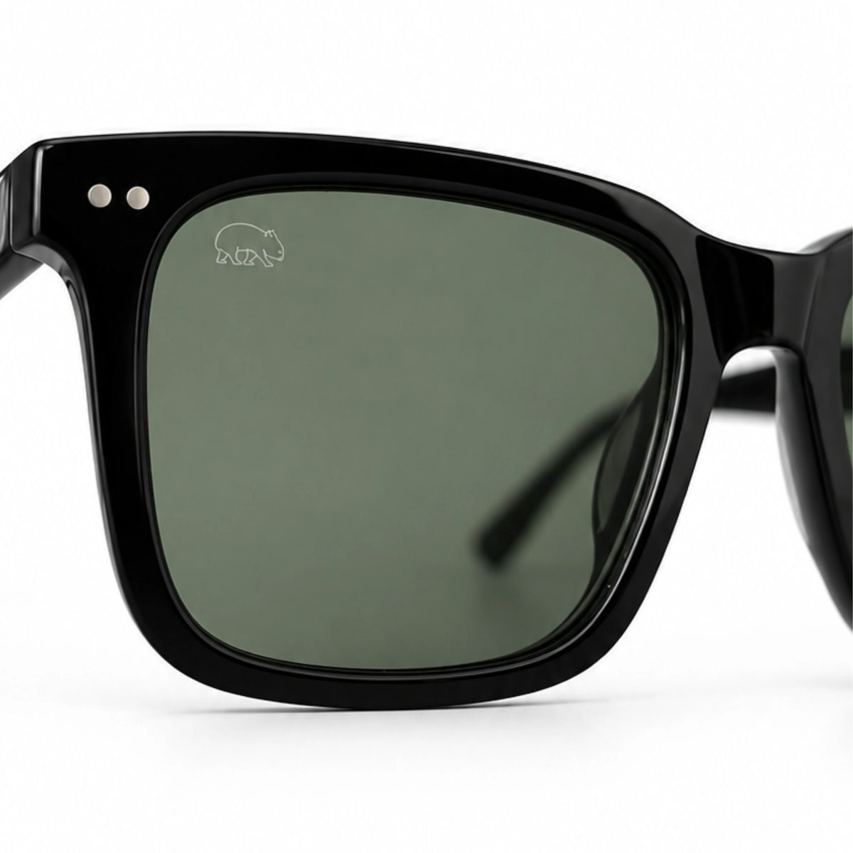 Close-up of Wombat Oslo grey-green polarised lens with etched wombat logo in satin black acetate frame