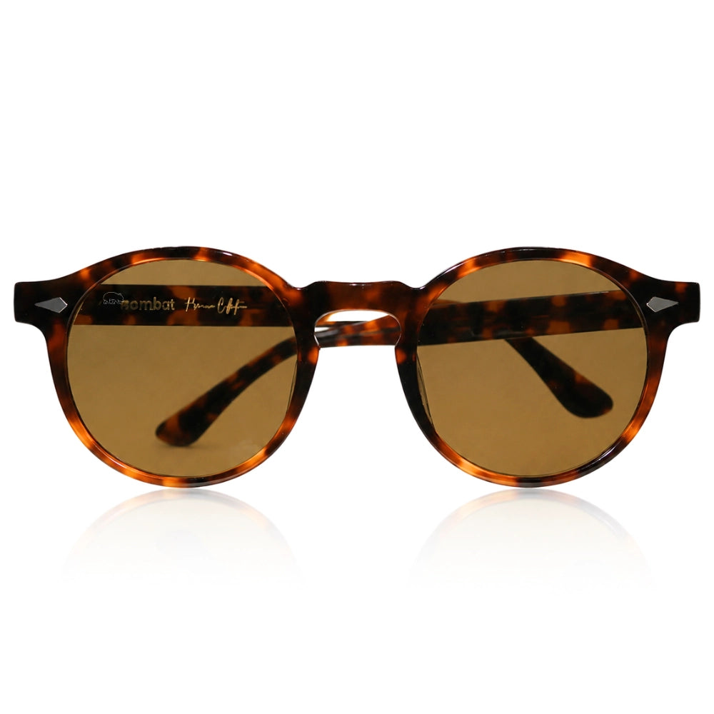 Round sunglasses with a brown tortoiseshell acetate frame and warm brown lenses, shown on a clean white background with a subtle reflection.